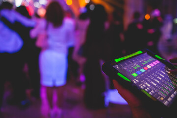 View of lighting technician with tablet, operator controlling sound and light during live event...