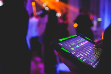 View of lighting technician with tablet, operator controlling sound and light during live event...