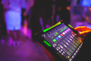 View of lighting technician with tablet, operator controlling sound and light during live event concert on stage show broadcast, technician with professional equipment, working on mixing console