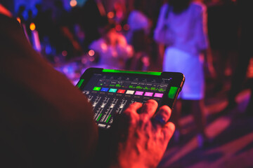 View of lighting technician with tablet, operator controlling sound and light during live event...