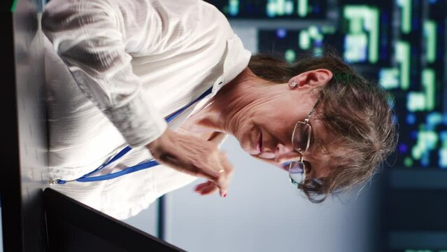 Vertical video Precise serviceman in cloud computing company housing high end servers capable of quickly and efficiently performing complex computations and data analysis, using tablet to root out