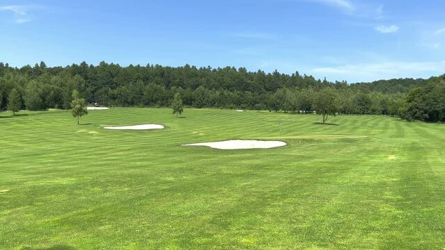 Beautiful golf course with hills, sand and trees. A view of the painted green golf course where the championship is held.