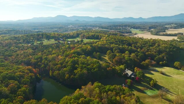 Aerial view of rural USA. Big luxury residential house surrounded with farm fields and dense woods in Appalachian region of North Carolina