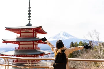 Photo sur Plexiglas Mont Fuji Happy Asian woman enjoy outdoor lifestyle travel at red Chureito Pagoda with Mt Fuji covered background in winter holiday vacation. People travel Japan landmark famous place and season change concept.