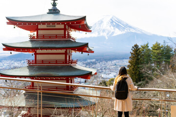 Happy Asian woman enjoy outdoor lifestyle travel at red Chureito Pagoda with Mt Fuji covered background in winter holiday vacation. People travel Japan landmark famous place and season change concept. - obrazy, fototapety, plakaty