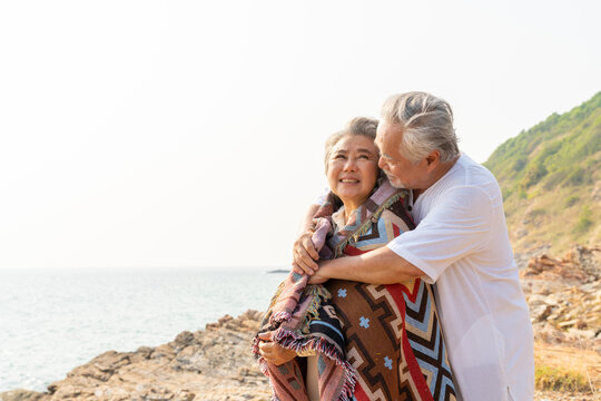 Asian Family Senior Couple Hugging Each Other On Coastline Beach At Sunset. Retirement Elderly People Enjoy Outdoor Lifestyle Travel Ocean On Summer Vacation. Old Person Mental Health Care Concept.