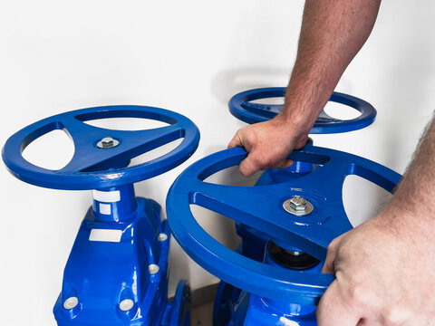 man holding a circle closing a large water valve (selective focus)