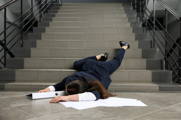 Unconscious woman with scattered folder and papers lying on floor after falling down stairs indoors