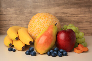 Delicious ripe fruits, blueberries and dried apricots on beige table, closeup