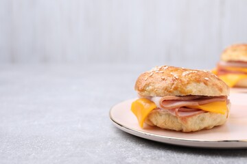 Delicious bagel with ham and cheese on light grey table. Space for text