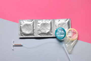 Condoms and intrauterine device on color background, flat lay. Choosing birth control method
