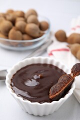 Bowl of tamarind sauce and fresh pods on light table