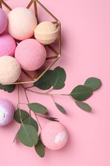 Bowl with bath bombs and eucalyptus leaves on pink background, flat lay
