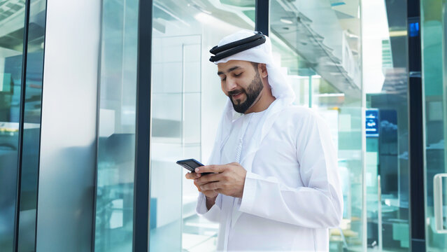 Arab businessman with high-rise buildings with glass windows as background. Arabic Man in Kandura Thobe Thawb for Middle Eastern corporate finance banking concept - Powered by Adobe
