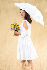 Bride stands with umbrella and flowers