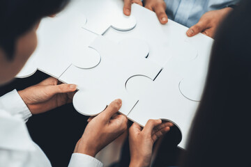 Diverse corporate officer workers collaborate in office, connecting puzzle pieces to represent...