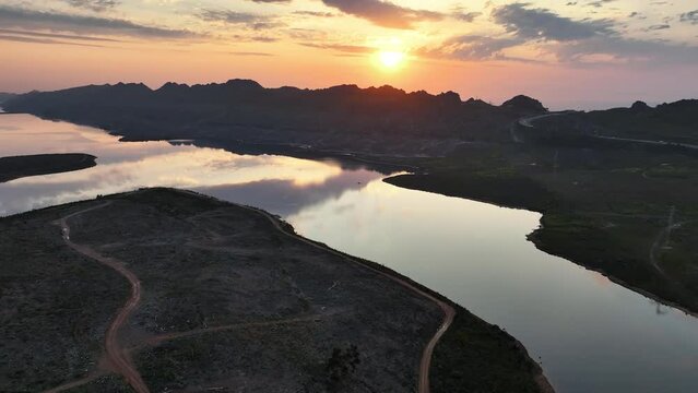 Sunset aerial view of Steenbras Dam, Cape Town, one of the City's major water supplies, on a windless evening. Steenbras Mountains and Sir Lowry's Pass  in background. Shot in D-log, slow right drift.