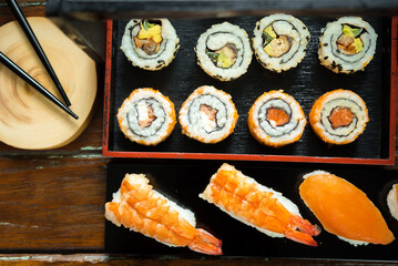 Sushi Set nigiri shrimp and salmon and sushi california rolls with avocado and maki with carrot, on wood,top view