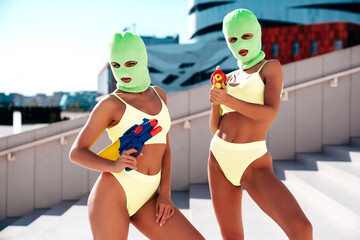 Two beautiful sexy women in green underwear. Models wearing bandit balaclava mask. Hot seductive...