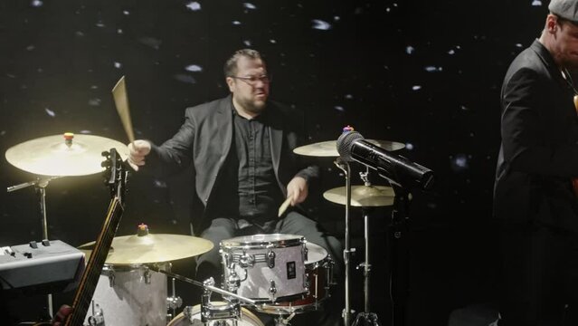 Musicians playing rock music at the concert. Male and female performers are performing on flash strobe illuminated stage. Artists with instruments in band at night.