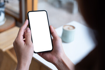 Mockup, woman's hand holding using mobile phone at coffee shop with copy space, white blank screen for text, mobile app design and advertising, online marketing
