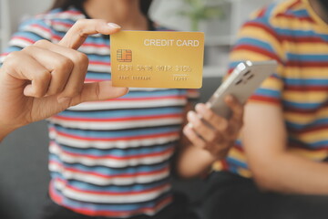 .Young couple use credit card for online shopping on internet website at home. Number on the credit card is mock up. No personal information shown on the credit card. Online business shopping concept.