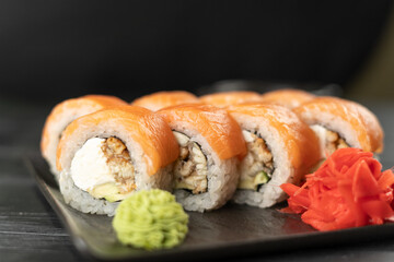 Sushi roll Philadelphia with smoked eel, salmon and cream cheese on a black background