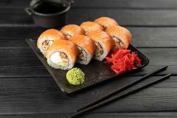 Top view of sushi with salmon and smoked eel on stone plate on wooden background served with wasabi and ginger