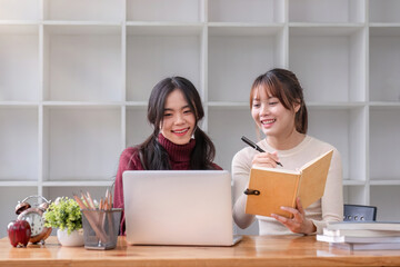 Two young female students tutoring and catching up workbook together