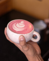 hand holding a cup of coffee pink latte