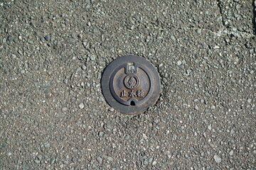 Obraz premium A manhole for a stopcock embedded in a city road. 