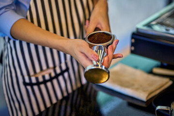 Barista will use tamper for press coffee before pass a coffee machine to make espresso shot.