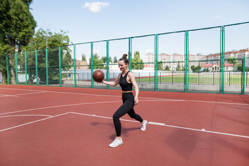 Fototapeta premium Athletic basketball player dribbles the ball on the basketball field.