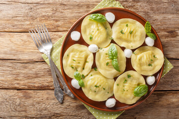 Cappellacci fresh filled pasta made with a delicious filling mozzarella and basil closeup on the plate on the wooden table. Horizontal top view from above