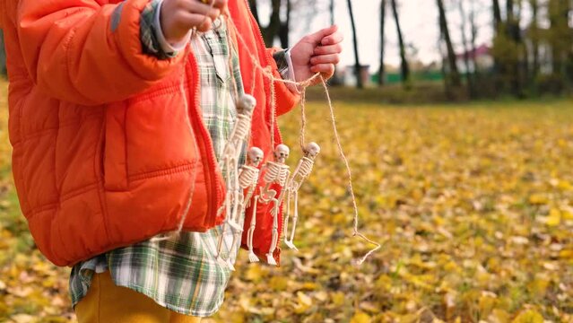 Decorative Skeletons hang on a rope in a children hands. Horizontal video