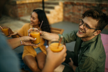 Group of people holding juices and mingling around the pool, all dressed up for a fun summer enjoyment. Focus on drinks