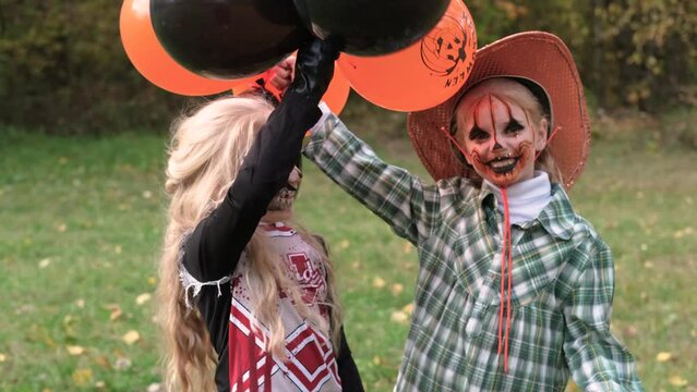 Two children girls girlfriends in Halloween costumes and makeup celebrate Halloween with black and orange balloons in their hands. Horizontal video