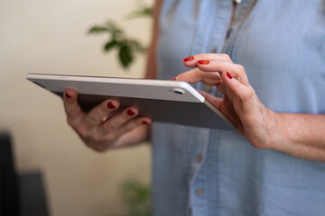 Unrecognizable Middle-Aged Woman Holding A Tablet. Concept Of Older Women And New Technologies. Senior Woman Using Digital Tablet. The Use Of Technology By The Elderly.