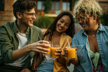 Loving diverse friends sitting, drinking, and talking at the backyard party.