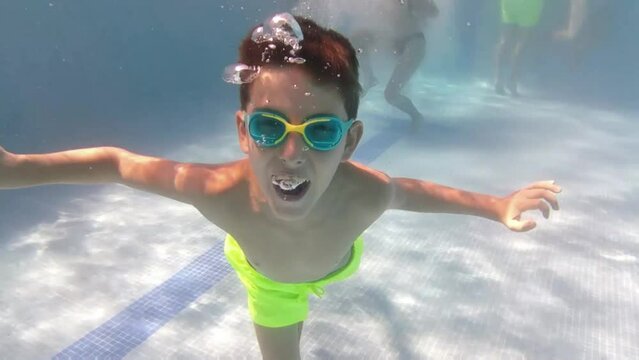 Little boy playing and swimming in pool under the water.