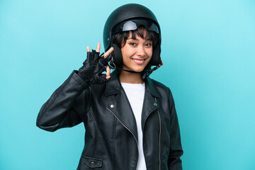 Young Argentinian woman with a motorcycle helmet isolated on blue background showing ok sign with fingers