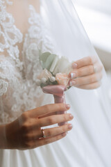bride is holding boutonniere in her hands. wedding flowers.
