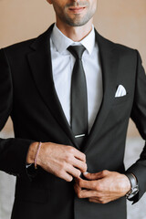 stylish man in a black classic suit with a tie. The groom is preparing for the wedding ceremony