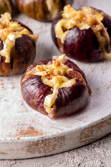Ripe figs baked with cow's-milk cheese brie and camambert and sprinkled with bread crumbs decorated with mint leaves on white background. Healthy eating concept.