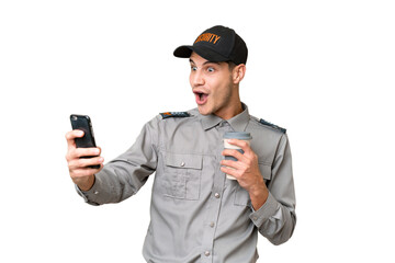 Young security man over isolated background holding coffee to take away and a mobile