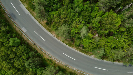 Aerial view captured by a drone showcasing the Alpine forest and a road - 633984069