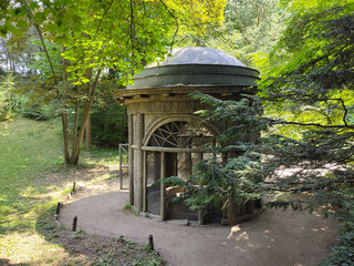 A wooden structure covered by trees in a park