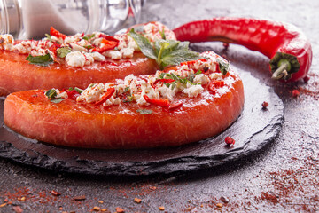 Grilled watermelon with feta cheese, chili pepper and mint. BBQ healthy food concept.  black background.