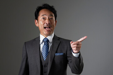 右側を指差すミドルエイジのビジネスマン　黒背景