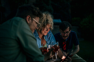 Friends looking together on the phone during a dinner party.